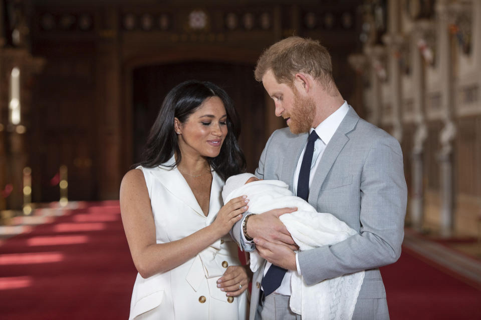 FILE - In this Wednesday May 8, 2019 file photo, Britain's Prince Harry and Meghan, Duchess of Sussex, pose during a photocall with their newborn son Archie, in St George's Hall at Windsor Castle, Windsor, south England. One of the most dramatic claims in Prince Harry and Meghan's interview with Oprah Winfrey was that their son was denied a royal title, possibly because of the color of his skin. Queen Elizabeth II has nine great-grandchildren, including Archie. They are not princes and princesses, apart from the three children of Prince William, who is second in line to the throne and destined to be king one day. (Dominic Lipinski/Pool via AP, File)