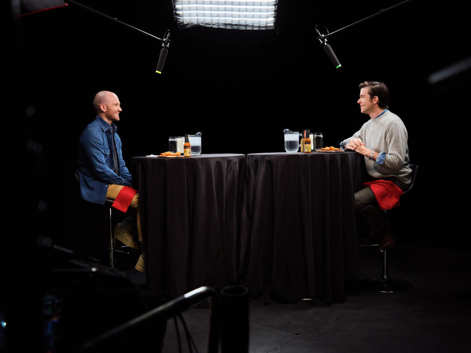 Sean Evans and John Mulanney sit across from each other on the set of 'Hot Ones' 