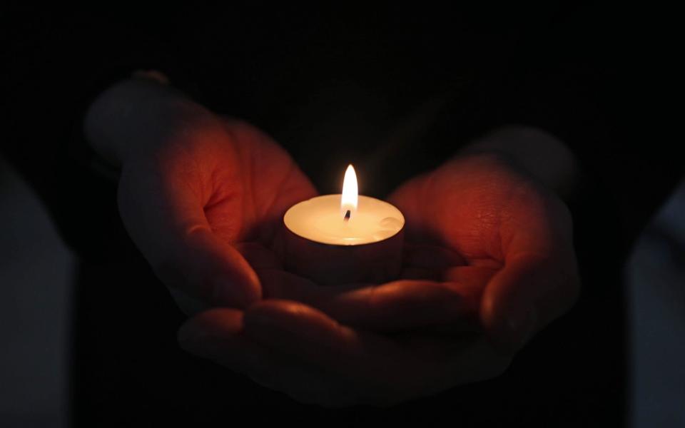 Rachel Fielding, Virger at Blackburn Cathedral, holds a lit candle during the National Day of Reflection -  Peter Byrne/PA