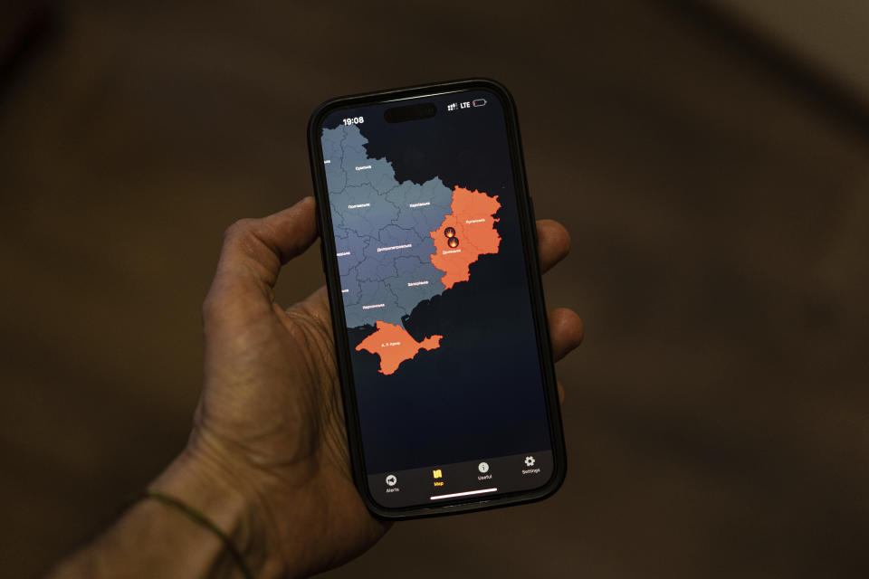 A man takes a photo of his smartphone in Kyiv, Ukraine Monday, March 27, 2023 showing the "Air Alert" application which shows regions currently under Russian rocket attacks. When air raid alarms sound in Ukraine, they also trigger the "Air Alert" downloadable app that has been voiced by “Star Wars” actor Mark Hamill. With his gravely but also calming baritone, he urges people to take cover. He also tells them when the danger has passed, signing off with “May the Force be with you.” (AP Photo/Evgeniy Maloletka)