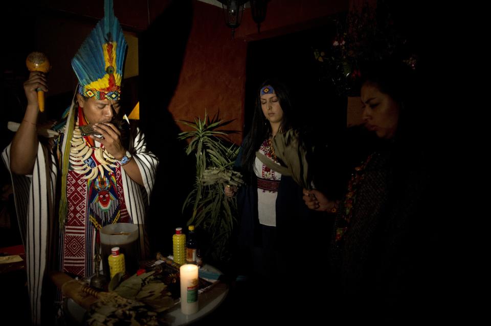 Picture taken on August 9, 2014 of a healer (L) starting a Yage ceremony  in La Calera, Cundinamarca department, Colombia. Yage, a mixture of the Ayahuasca hallucinogenic liana and a psychoactive bush, attracts many people in Colombia, who seek to participate in a traditional indigenous ritual of spiritual and physical healing impossible to realize in many countries where these plants are considered drugs. AFP PHOTO/EITAN ABRAMOVICH        (Photo credit should read EITAN ABRAMOVICH/AFP via Getty Images)