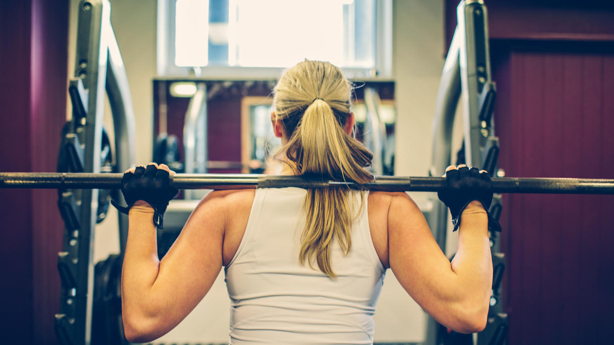  Strong woman exercising in the gym using weights. 