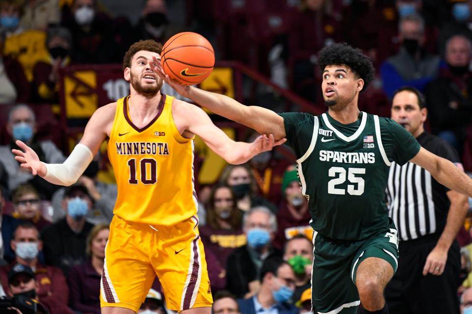 Michigan State guard Malik Hall (25) reaches for a rebound before Minnesota forward Jamison Battle can get to it during the first half of an NCAA college basketball game Wednesday, Dec. 8, 2021, in Minneapolis.