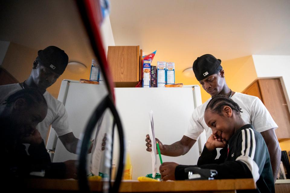 Sinaca Wagoner, Sr., helps his son Sinaca Wagoner, Jr., 7, with his school work in their apartment in Lower Price Hill on Thursday, April 2, 2020. Sinaca Jr. is in the second grade at Cincinnati College Preparatory Academy.