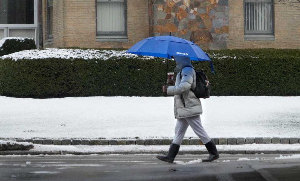 A pedestrian keeps dry from above and below while walking east on Angell Street in Providence in Sunday morning's rain-snow mix. [Kris Craig/Providence Journal]