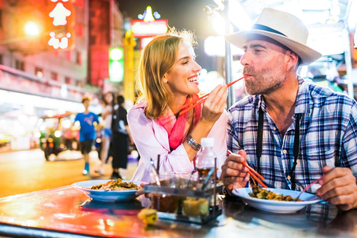 Middle-aged man and his companion handsome blond lady on a tuk-tuk ride in Bangkok