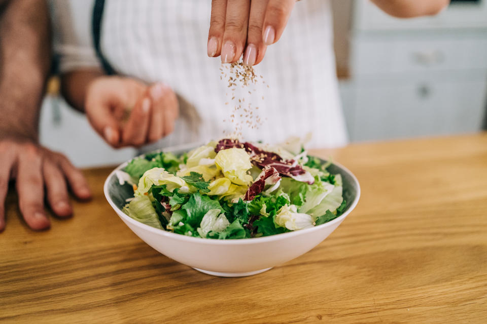 Cropped shot of young woman preparing tasty salad in her kitchen.