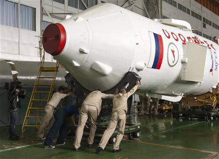 Specialists move the Soyuz TMA-16 spacecraft in the assembling hangar at the Baikonur cosmodrome, September 27, 2009. In Baikonur as elsewhere, the once-pioneering space sector is struggling to live up to its legacy, end an embarrassing series of botched launches, modernise decaying infrastructure and bring in new blood and new ideas. REUTERS/Shamil Zhumatov