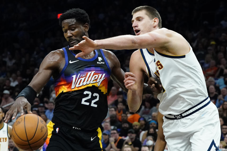 Denver Nuggets center Nikola Jokic (15) battles Phoenix Suns center Deandre Ayton (22) for the ball during the first half of an NBA basketball game, Wednesday, Oct. 20, 2021, in Phoenix. (AP Photo/Matt York)