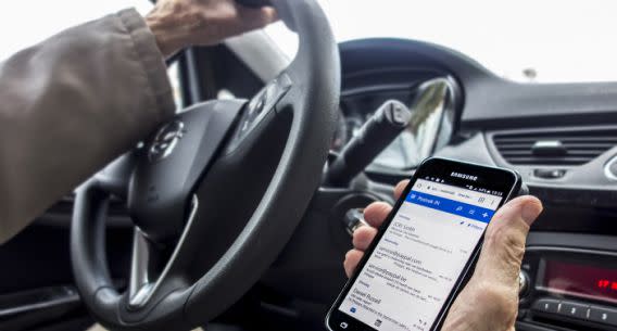 A man checking his messages at the wheel. (GETTY)