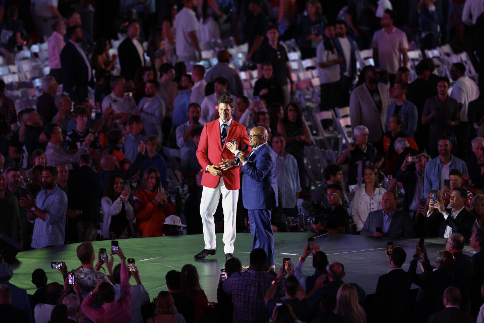 Tom Brady and Mike Tirico are seen on stage during Brady's Hall of Fame induction ceremony