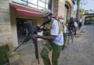 An armed member of Kenyan security forces runs through a hotel complex in Nairobi, Kenya Tuesday, Jan. 15, 2019. Terrorists attacked an upscale hotel complex in Kenya's capital Tuesday, sending people fleeing in panic as explosions and heavy gunfire reverberated through the neighborhood. (AP Photo/Ben Curtis)