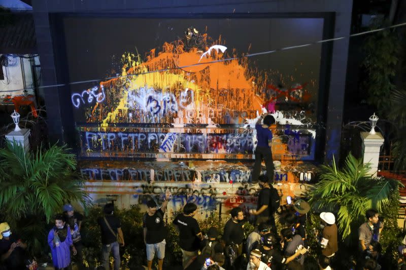 Demonstrators stand in front of the spray-painted plaque with lettering in front of the police headquarters during a rally in Bangkok