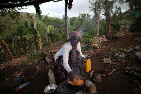 Tipiti cooks pasta as she combs her daughter's hair in Boucan Ferdinand, Haiti, April 8, 2018. REUTERS/Andres Martinez Casares