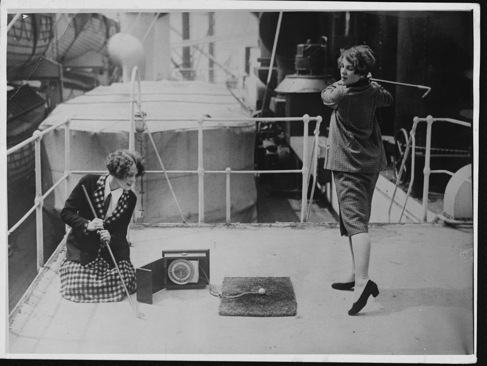 Two women practice their golf swings on the deck of the cruise ship S.S. California.