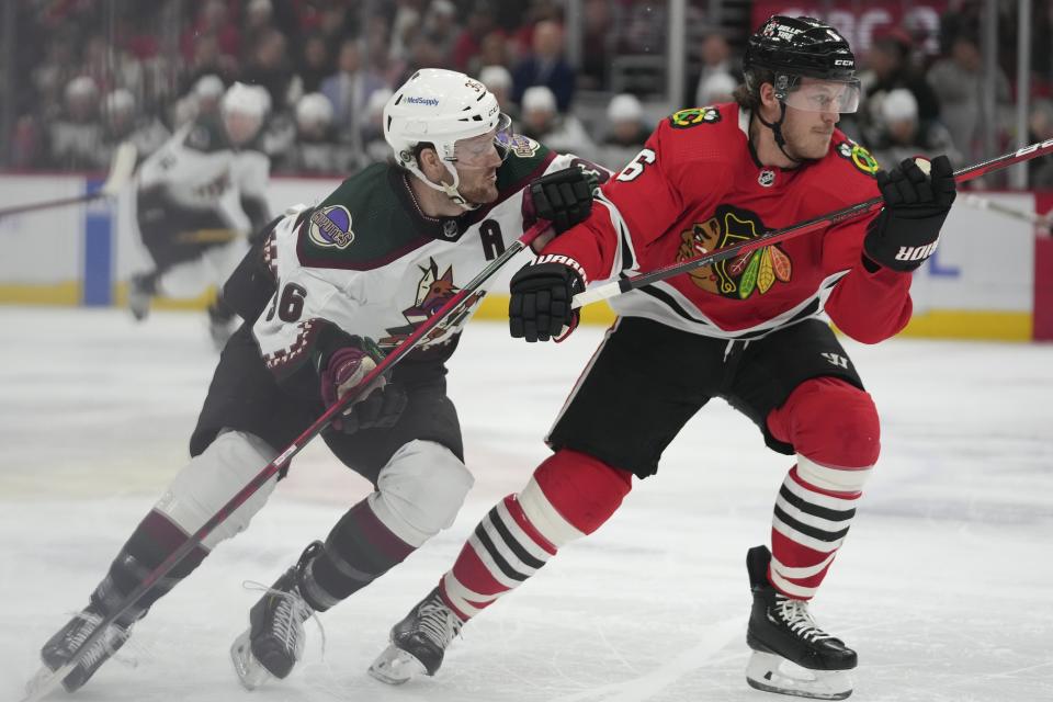 Arizona Coyotes right wing Christian Fischer (36) and Chicago Blackhawks defenseman Jake McCabe (6) struggle together as they go after the puck during the first period of an NHL hockey game Friday, Jan. 6, 2023, in Chicago. (AP Photo/Erin Hooley)
