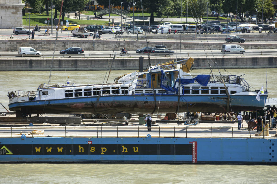 FILE - In this Tuesday, June 11, 2019 file photo, a crane places the wreckage of the Hableany sightseeing boat on a transporting barge at Margaret Bridge, the scene of the fatal boat accident in Budapest, Hungary. Hungarian police say that the deceased captain of the tour boat which sank after colliding with a river cruise ship on the Danube River was not to blame for the deadly incident. Twenty-eight people, mostly South Korean tourists, aboard the Hableany (Mermaid) sightseeing boat died after their vessel collided with the Viking Sigyn river cruise ship on May 29. The remains of a South Korean tourist have yet to be recovered. (Balazs Mohai/MTI via AP, file)
