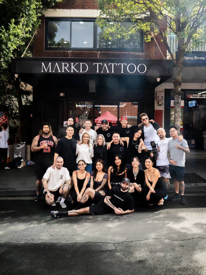 A group of people, including Markd Tattoo staff and clients, posing happily together outside the Markd Tattoo shop