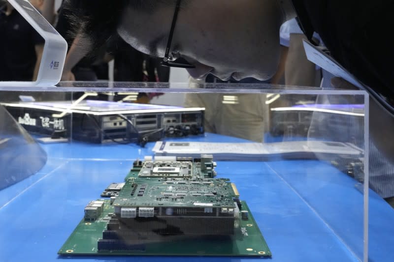 <cite>2023年7月5日，在上海舉行的世界AI大會期間，一位民眾正在觀看中國生產的晶片組。（美聯社）</cite>