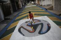 Gabriel, 14, plays soccer on graffiti painted with the official match ball for the 2014 World Cup named "Brazuca" on a street in Sao Paulo May 14, 2014. The city of Sao Paulo will host the opening match of the 2014 Brazil World Cup. REUTERS/Nacho Doce (BRAZIL - Tags: SPORT SOCCER WORLD CUP SOCIETY)