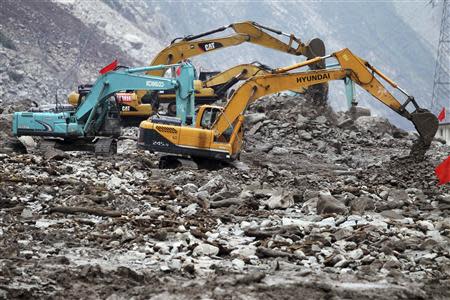 Excavators remove rocks on the State Highway 213, which has been cut off by mudslides in Wenchuan, Sichuan province in this July 6, 2011 file photo. REUTERS/China Daily/Files