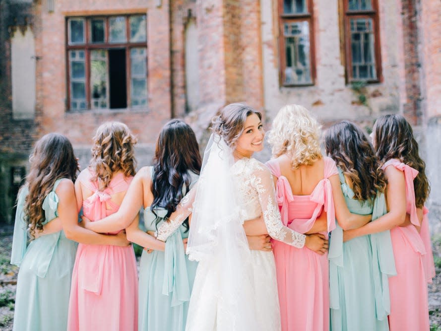 Bride in veil with bridesmaids in blue and pink dresses
