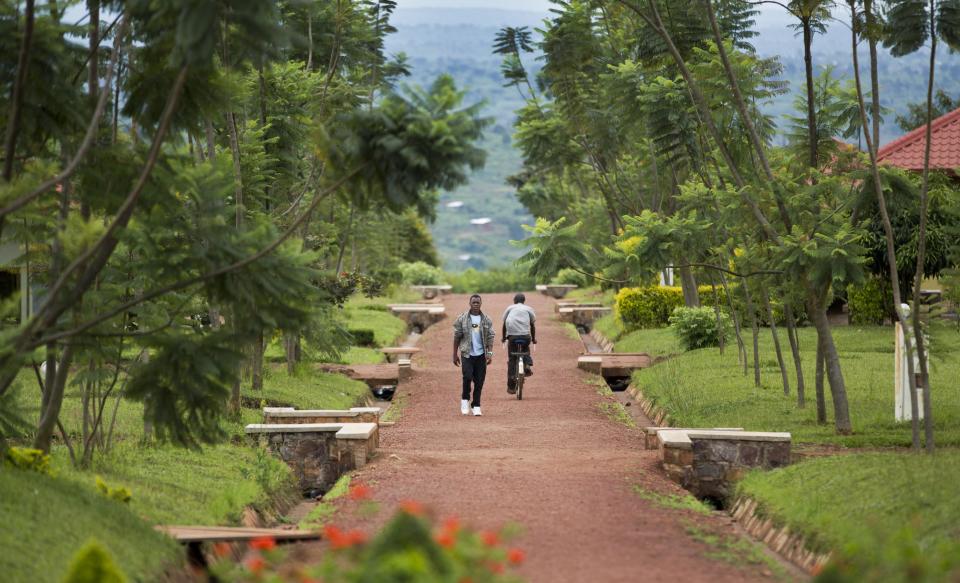 In this photo taken Monday, March 24, 2014, a Rwandan student walks in the grounds of the Agahozo-Shalom Youth Village near Rwamagana, in Rwanda. Most of the kids in a school set amid the lush green, rolling hills of eastern Rwanda don't identify themselves as Hutu or Tutsi. That's a positive sign for Rwanda, which is now observing the 20th anniversary of its genocide, a three-month killing spree that, according to the official Rwandan count, left more than 1 million people dead, most of them Tutsis killed by Hutus. The teenagers attending the Agahozo-Shalom Youth Village, a school with dorms that creates tight-knit student families, say the ethnic slaughter that their parents or grandparents were a part of either as victims or perpetrators won't be repeated. The school director echoes the sentiment. (AP Photo/Ben Curtis)