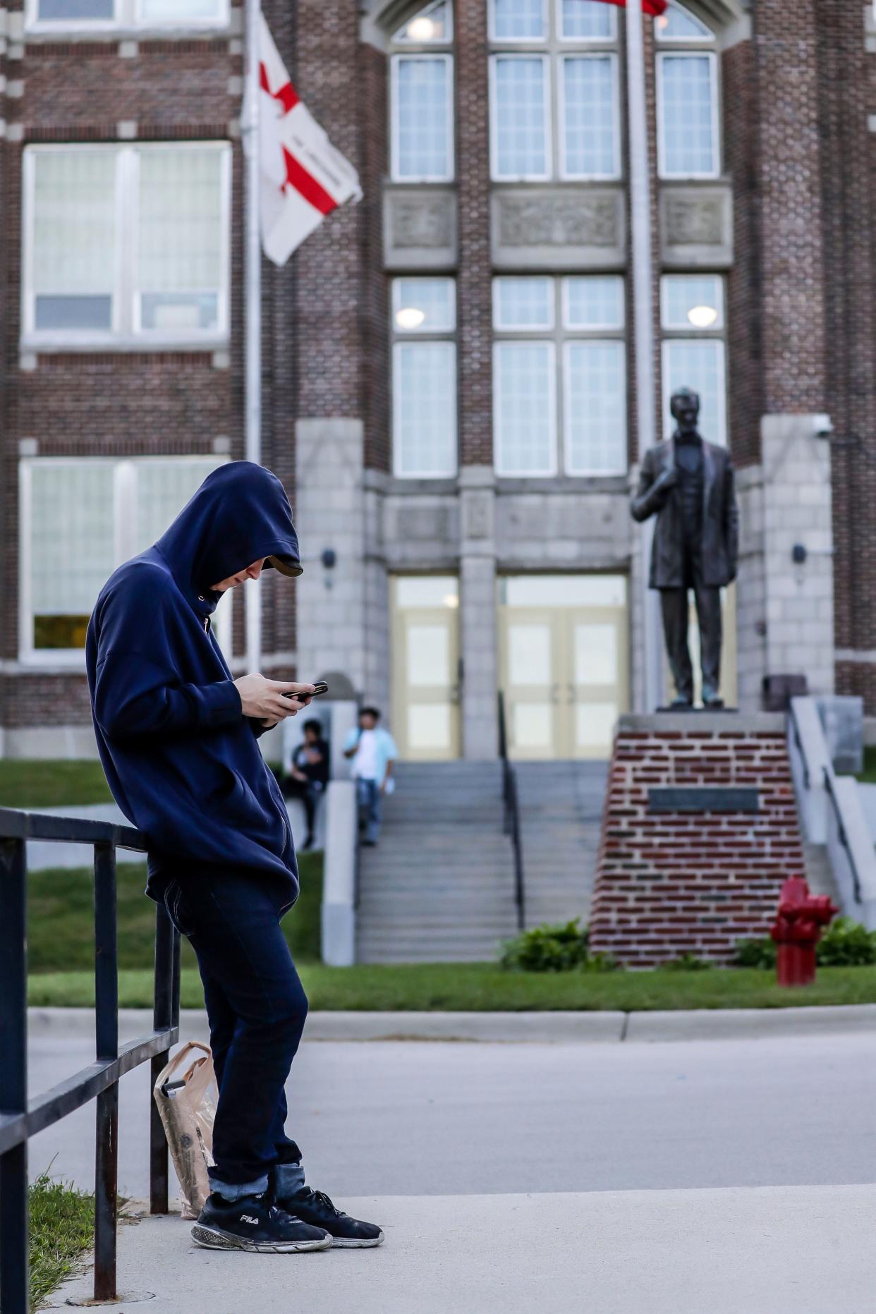 FILE - A Manitowoc Lincoln sophomore checks messages on his phone before the first day of school on Aug. 30, 2022.