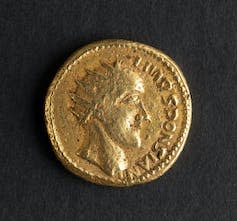 Gold coin with profile of man's head wearing a crown.