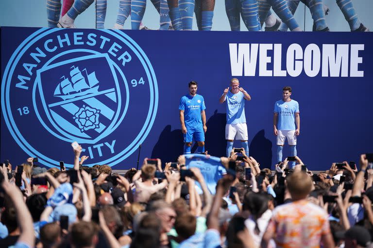 Julián Álvarez, derecha, Erling Haaland, centro, y Stefan Ortega Moreno son vitoreados por los fanáticos del Manchester City durante la presentación de los refuerzos del equipo de la Liga Premier, en Manchester, Inglaterra, el domingo 10 de julio de 2022. (AP Foto/Dave Thompson)