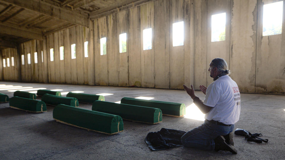 A man prays by the coffins of victims inside the former UN base in Potocari, near Srebrenica, Bosnia, Friday, July 10, 2020. Nine newly found and identified men and boys will be laid to rest when Bosnians commemorate on Saturday 25 years since more than 8,000 Bosnian Muslims perished in 10 days of slaughter, after Srebrenica was overrun by Bosnian Serb forces during the closing months of the country's 1992-95 fratricidal war, in Europe's worst post-WWII massacre. (AP Photo/Kemal Softic)