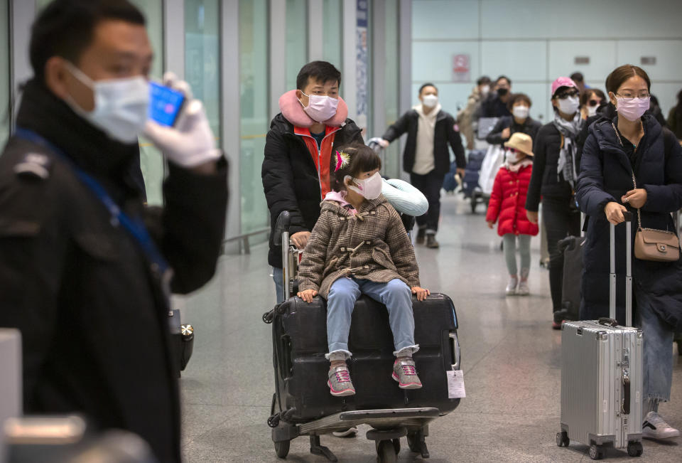 Travelers wearing face masks enter the international arrivals area at Beijing Capital International Airport in Beijing, Thursday, Jan. 30, 2020. China counted 170 deaths from a new virus Thursday and more countries reported infections, including some spread locally, as foreign evacuees from China's worst-hit region returned home to medical observation and even isolation. (AP Photo/Mark Schiefelbein)
