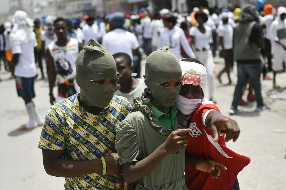 Children with their faces covered, join a march led by Jimmy Cherizier, alias Barbecue, a former police officer who heads a gang coalition known as "G9 Family and Allies," to demand justice for slain Haitian President Jovenel Moise in La Saline neighborhood of Port-au-Prince, Haiti, Monday, July 26, 2021. Moise was assassinated on July 7 at his home. (AP Photo/Matias Delacroix)
