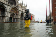 FILE - In this Tuesday, Dec. 8, 2020 file photo, people wade their way through water in flooded St. Mark's Square following a high tide, in Venice, Italy. Lashing winds that pushed 1.87 meters (nearly 6 feet 2 inches) of water into Venice in November 2019 and ripped the lead tiles off St. Mark’s Basilica for the first time ever shocked Venetians with the city’s second-worst flood in history, but it was the additional four exceptional floods over the next six weeks that triggered fears about the impact of worsening climate change. (Anteo Marinoni/LaPresse via AP, file)