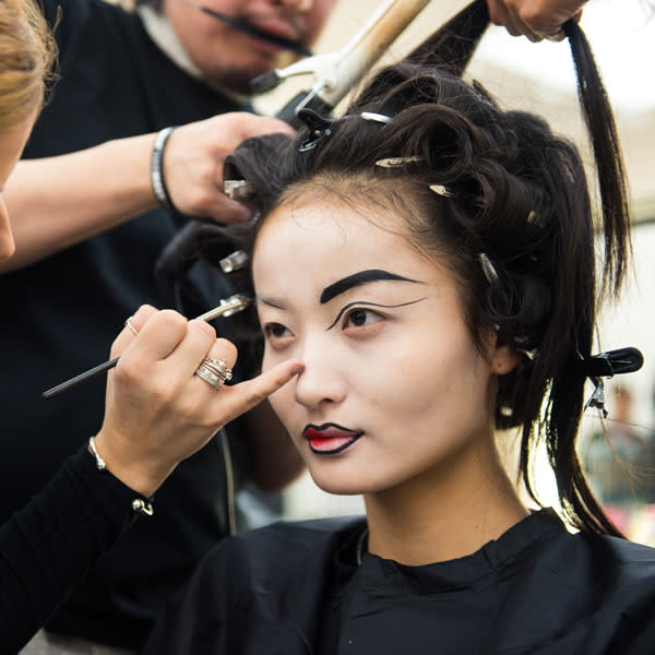 Hair stylists and make-up artists get to work on a Vivienne Westwood model © Getty