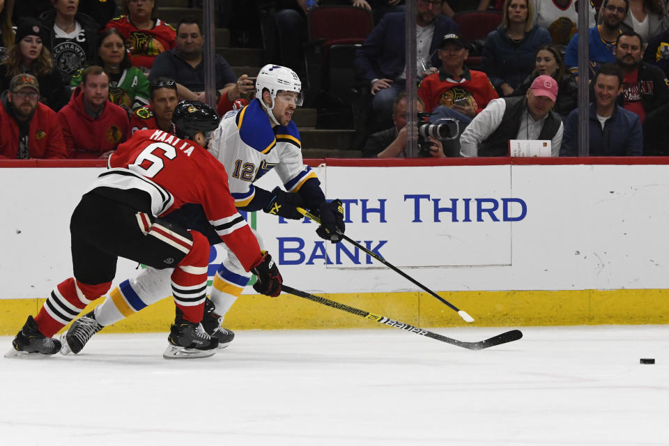 Chicago Blackhawks defenseman Olli Maatta (6) and St. Louis Blues left wing Zach Sanford (12) move the puck during the first period of an NHL hockey game between the Chicago Blackhawks and the St. Louis Blues on Sunday March 8, 2020, in Chicago. (AP Photo/Matt Marton)