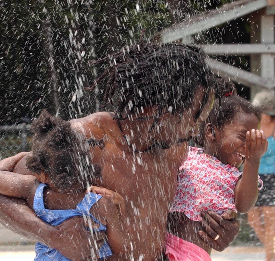 On Father's Day in 2004, Darryl Washington carries his daughter Nysich and niece GiGi Walker into the kids' splash park at Hanna.