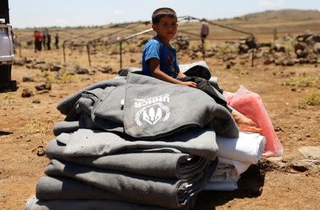 Internally displaced child from Deraa province sits on blankets near the Israeli-occupied Golan Heights, in Quneitra, Syria June 21, 2018. REUTERS/Alaa al-Faqir