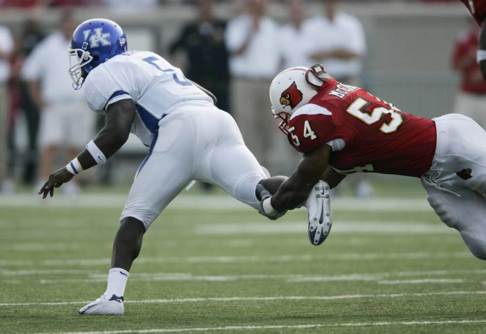 UK’s Arliss Beach is held back by UL’s Robert McCune as UK plays UL in Papa John’s Stadium in Louisville, Ky., on 9/5/04. UL beat UK 28-0. David Stephenson/staff.