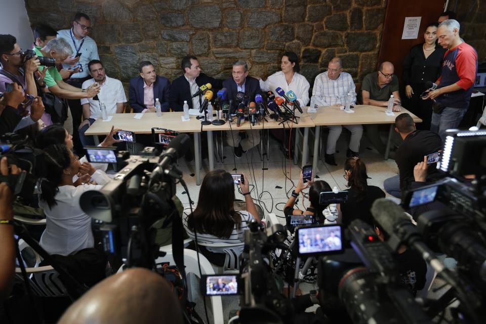 Spokesperson Gerardo Blyde, center, accompanied by members of the Delegation of the Unitary Platform for Negotiation, speaks during a press conference the day after the Supreme Court ratified the disqualification of opposition presidential candidate María Corina Machado, in Caracas, Venezuela, Saturday, Jan. 27, 2024. (AP Photo/Jesus Vargas)