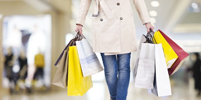 person walking through a mall with shopping bags in both hands