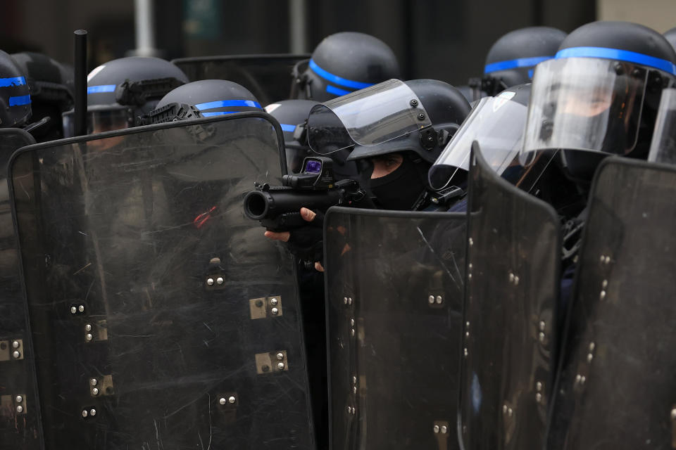 FILE - A riot police officer aims during clashes as part of a demonstration in Paris, on March 7, 2023. French President Emmanuel Macron has ignited a firestorm of anger with unpopular pension reforms that he rammed through parliament. Young people, some of them first-time demonstrators, are joining protests against him. Violence is also picking up. (AP Photo/Aurelien Morissard, File)