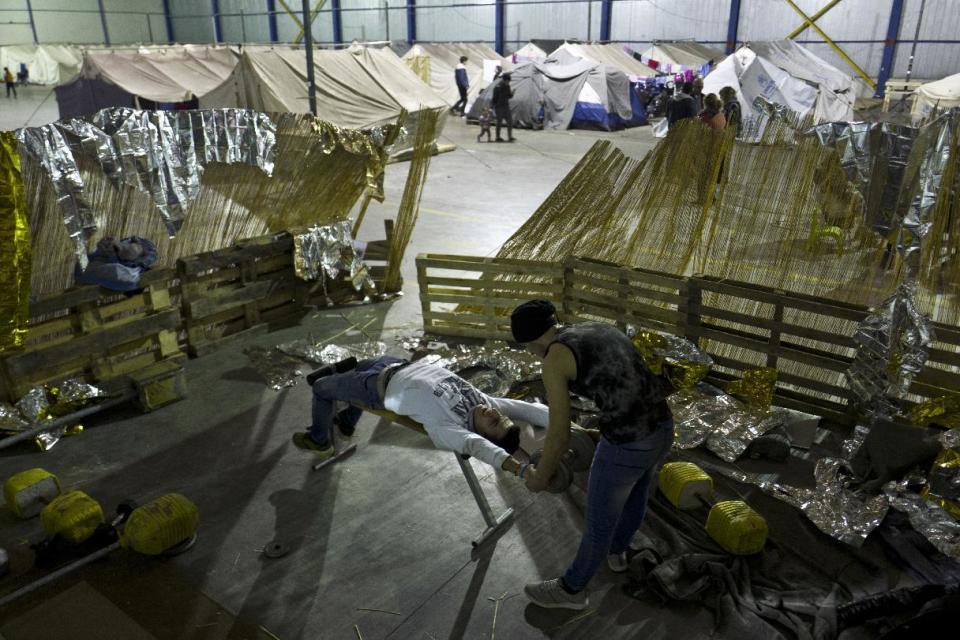 In this Wednesday, Jan. 18, 2017 photo, Syrian refugee men lift weights while practicing at a makeshift gym in Frakapor refugee camp on the outskirts of the northern Greek city of Thessaloniki. (AP Photo/Muhammed Muheisen)