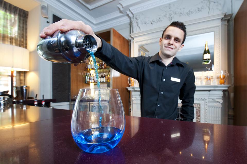 Bartender preparando un cóctel con curazao