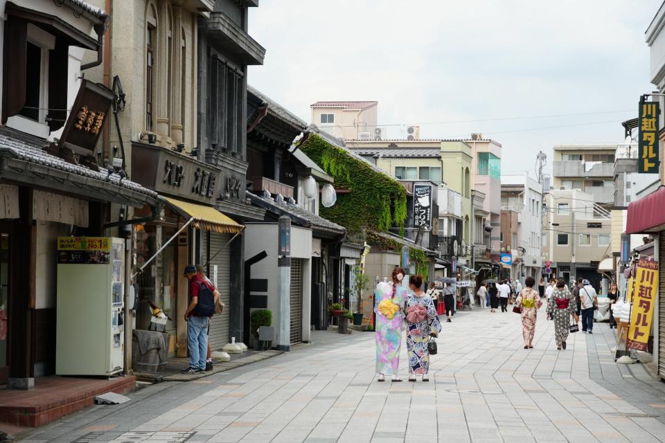 Two tourists in kimonos stand in the middle of Taisho Roman Street in Kawagoe.