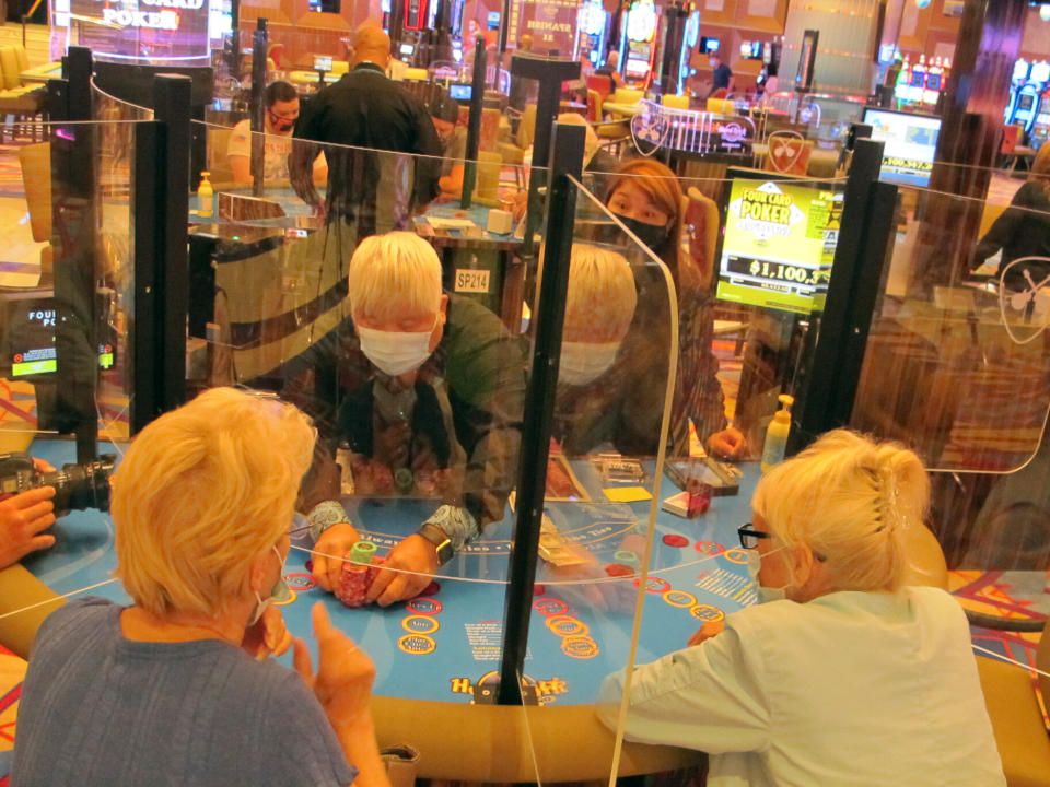 A dealer pushes a stack of chips to a winning gambler at the Hard Rock casino in Atlantic City, N.J. on July 2, 2020, the day the casino reopened amid the coronavirus outbreak. New Jersey's casinos and horse tracks won $264.5 million in July, a figure that was down nearly 21% from a year ago, but one the gambling houses will gladly take after months of inactivity. (AP Photo/Wayne Parry)