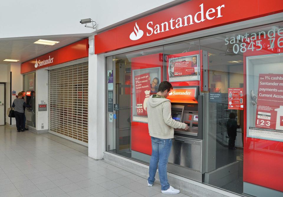 Customers use ATM machines at the Surrey Quays branch of Santander Bank, whilst the premises remain closed , in Surrey Quays, south London, September 13, 2013. Twelve men have been arrested over an alleged attempt to take control of Santander UK's computer systems and steal millions of pounds, British police said on Friday. The men are accused of fitting a device to a computer at a Santander branch in Surrey Quays, London, enabling them to take control of the bank's computers remotely, police said in a statement. The arrests were made by the Metropolitan Police's Central e-Crime Unit in London on Thursday. REUTERS/Toby Melville (BRITAIN - Tags: BUSINESS CRIME LAW)