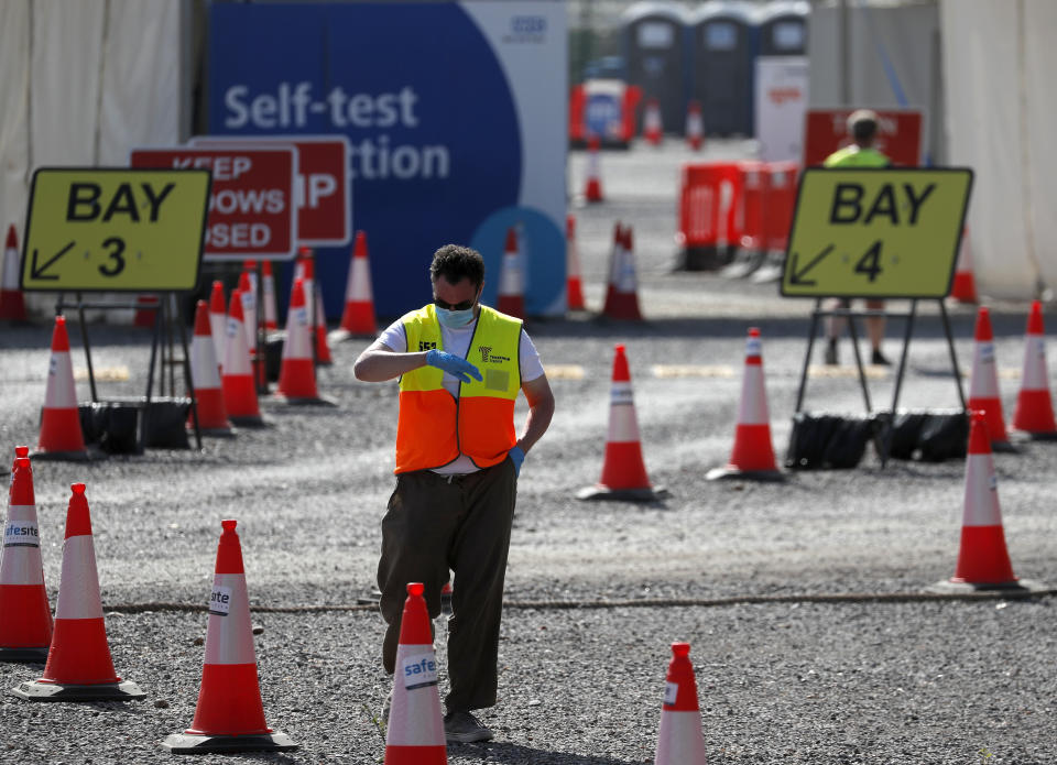 A staff member waits at empty lanes of a Covid-19 drive thru testing facility at Twickenham stadium in London, Thursday, Sept. 17, 2020. Britain has imposed tougher restrictions on people and businesses in parts of northeastern England on Thursday as the nation attempts to stem the spread of COVID-19, although some testing facilities remain under-utilised. (AP Photo/Frank Augstein)