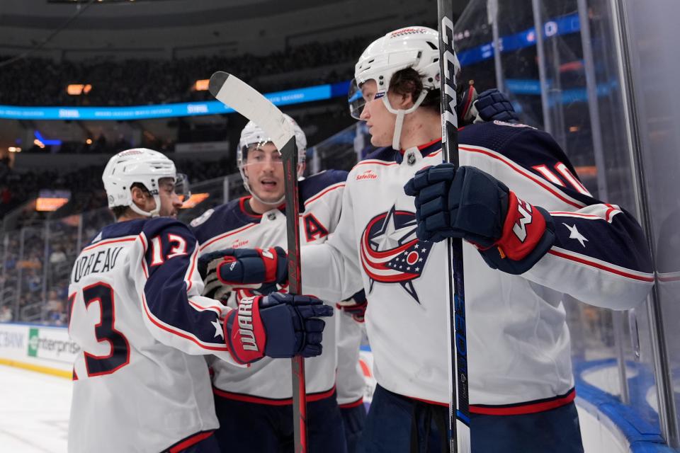 Columbus Blue Jackets' Dmitri Voronkov, right, is congratulated by teammates Zach Werenski and Johnny Gaudreau (13) after scoring during the third period of an NHL hockey game against the St. Louis Blues Tuesday, Jan. 30, 2024, in St. Louis. (AP Photo/Jeff Roberson)