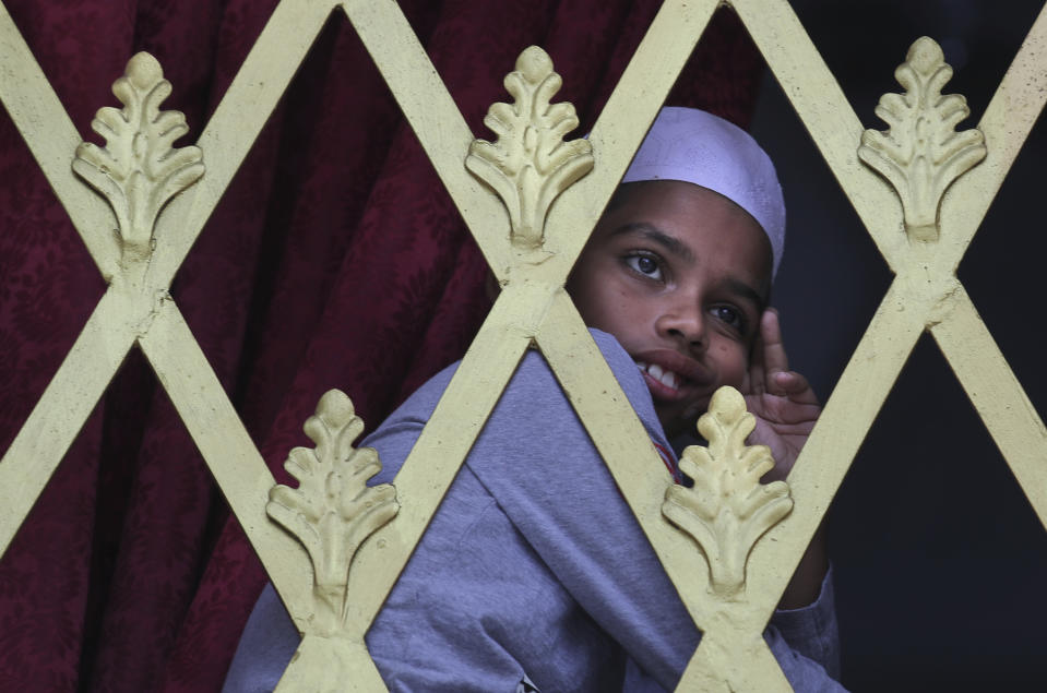 FILE - In this Friday, April 26, 2019 file photo, a Sri Lankan Muslim boy looks out from the window of a Mosque before Friday prayers in Colombo, Sri Lanka. Authorities had told Muslims to pray at home rather than attend communal Friday prayers that are the most important religious service for the faithful. At one mosque in Colombo where prayers were still held, police armed with Kalashnikov assault rifles stood guard outside. (AP Photo/Manish Swarup, File)